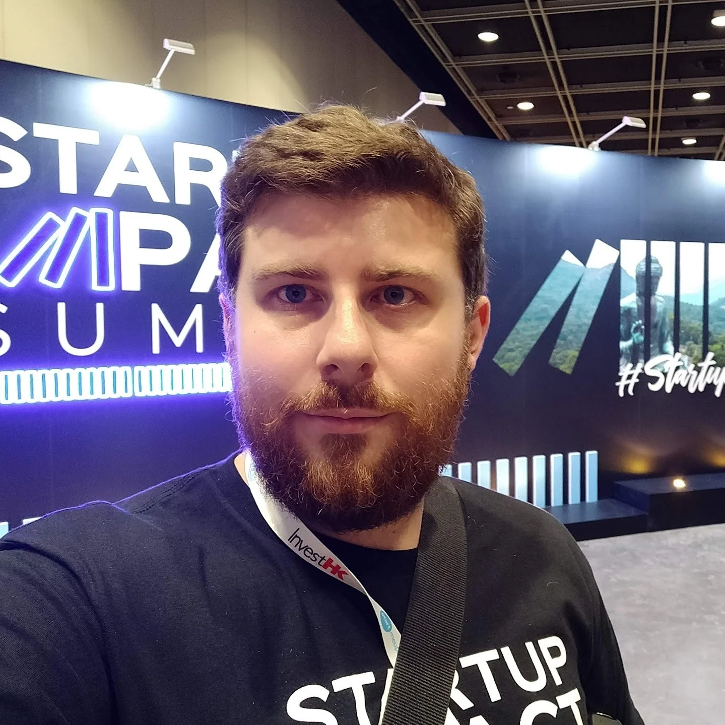 Gary Moran at the StartupImpact Summit, exhibition signage lit behind him