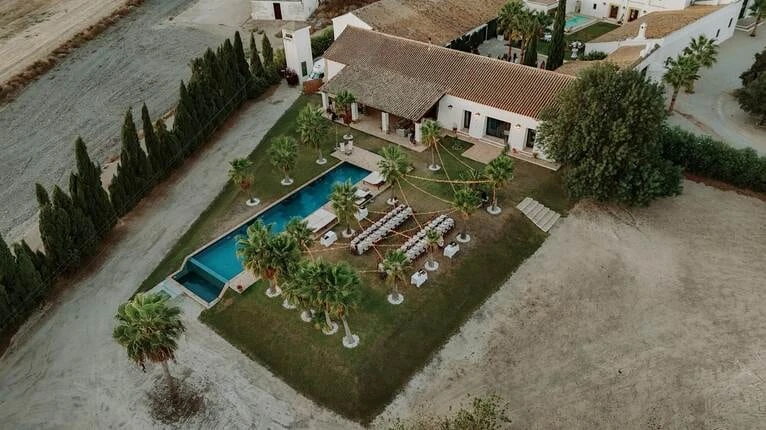 Aerial view of a wedding venue near Jerez de la Frontera — a country house with a pool, palm trees and tables set out for a celebration